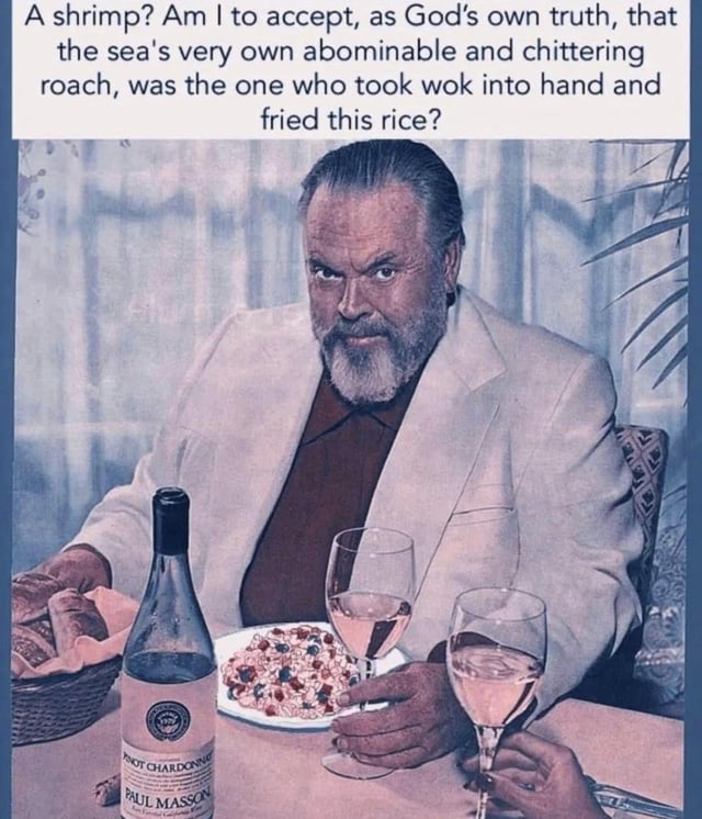 This is a single-panel meme featuring a vintage image of actor Orson Welles seated at a dining table. In front of him are a plate of fried rice, a Paul Masson Pinot Chardonnay wine bottle, two glasses of rose wine, and a basket of bread. Welles looks directly at the viewer with a stern, disbelieving, overly serious expression. Text placed above the image reads: "A shrimp? Am I to accept, as God's own truth, that the sea's very own abominable and chittering roach, was the one who took wok into hand and fried this rice?". The joke relies on absurdity and tone mismatch: it presents the ridiculous premise that the shrimp ingredient in shrimp fried rice is an intelligent creature that cooked the dish itself, delivered in a pretentious, overly formal dramatic tone that matches Orson Welles' famous sophisticated public persona.