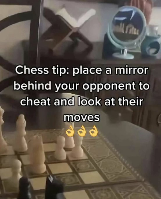 This humorous meme image displays a chessboard with light-colored pieces in the foreground. A small tabletop mirror is positioned behind the opponent's side of the board. Overlaid white text reads "Chess tip: place a mirror behind your opponent to cheat and look at their moves" followed by three OK hand emojis. The joke is sarcastic: the mirror is angled to reflect the poster's own chess pieces, not the opponent's, so the suggested 'cheat' is completely useless and absurd, mocking overly complicated bad advice for winning games.