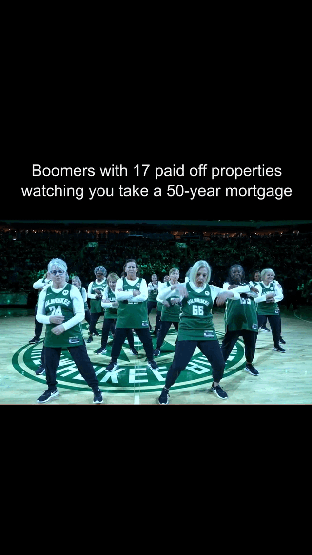 The image features a group of older adults (presumed to represent Baby Boomers) performing an energetic, synchronized dance on a basketball court. They are wearing green jerseys with "Milwaukee" printed on the front, numbered 74, 66, and others. The court has a large circular logo, likely associated with a basketball team (possibly the Milwaukee Bucks). Above the dancers, bold white text reads: "Boomers with 17 paid off properties watching you take a 50-year mortgage." The humor stems from the contrast between the Boomers' apparent financial stability (multiple paid-off properties) and the younger generation's burden of long-term mortgages, highlighted by the dancers' joyful, carefree movements.