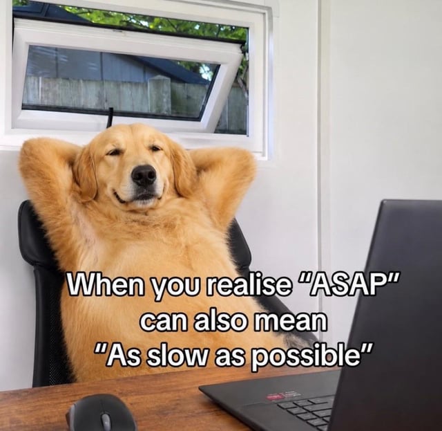This meme displays a golden retriever sitting comfortably in an office chair, leaning back with its paws propped behind its head, wearing a smug, totally relaxed and unbothered expression. It is positioned at a wooden work desk in front of an open laptop and mouse, with a small window in the background. Overlaid text delivers a humorous pun on the common acronym "ASAP": instead of the standard meaning "As Soon As Possible", the joke reinterprets the acronym as "As Slow As Possible", perfectly capturing the relatable, procrastinatory attitude many people have when asked to complete a task on an urgent timeline.