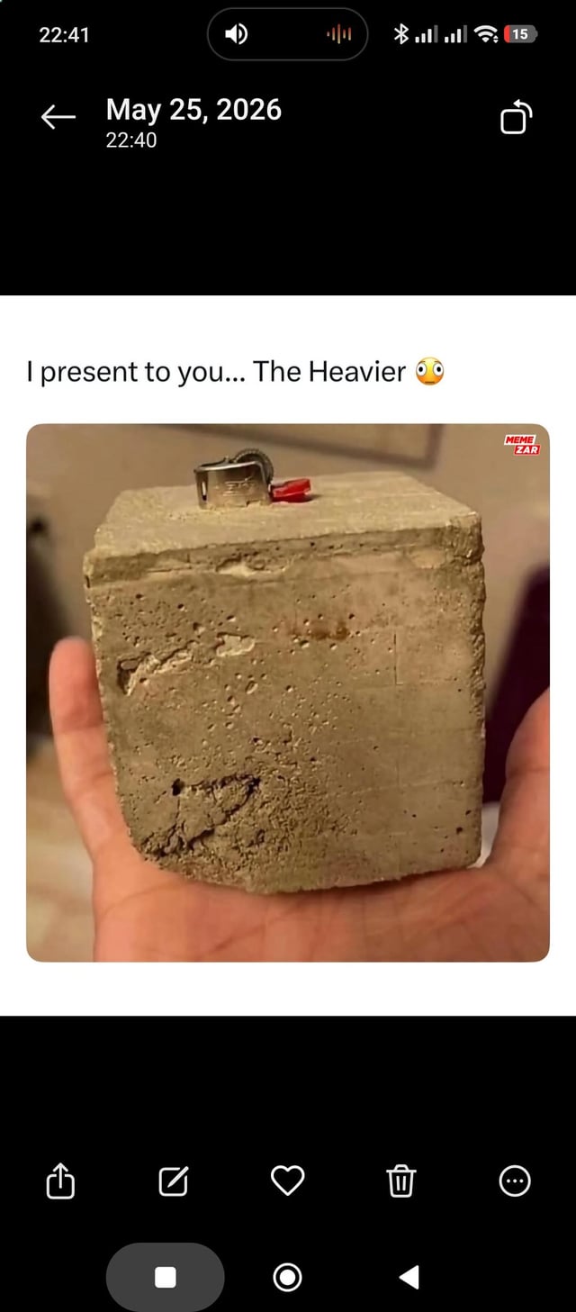 This meme screenshot displays a person's open palm holding a large, rough, porous solid concrete block. A small standard disposable lighter is placed on the top surface of the concrete block. The text above the image reads 'I present to you... The Heavier' paired with a wide-eyed shocked emoji. The joke is a simple visual pun: the object on top is a lighter (the noun, referring to the fire-starting tool), so the far heavier concrete block underneath it is humorously labeled 'the heavier', playing on the opposite adjective meanings of light (low weight) and heavy (high weight). The screenshot also includes mobile phone UI elements: the date May 25, 2026 is shown at the top, standard Android navigation buttons are visible at the bottom, and a 'MEME ZAR' watermark is present on the top right corner of the image content.
