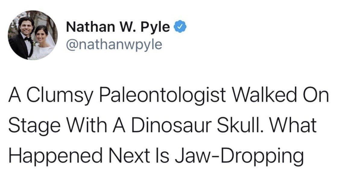 This image is a screenshot of a verified post from the X (formerly Twitter) social media platform. The post is a humorous pun from creator Nathan W. Pyle, formatted to mimic common viral clickbait headlines. The core text reads: 'A Clumsy Paleontologist Walked On Stage With A Dinosaur Skull. What Happened Next Is Jaw-Dropping.' The joke relies on the double meaning of the idiom 'jaw-dropping': the standard figurative definition meaning 'shocking or surprising', and the literal interpretation that the clumsy paleontologist dropped the dinosaur skull's jaw. The top left of the screenshot displays the poster's profile picture, a wedding photo of Nathan W. Pyle and his spouse, alongside his verified display name and @nathanwpyle handle.