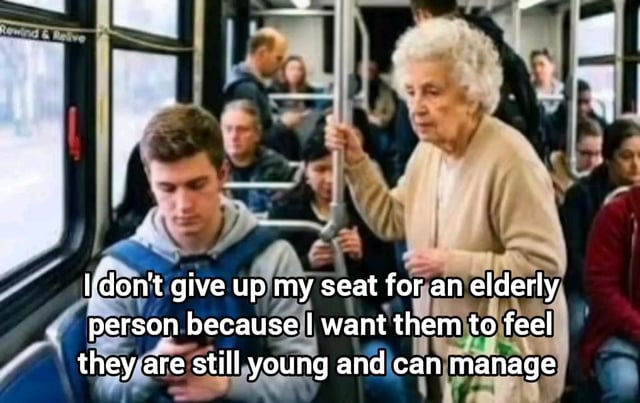 The meme takes place inside a crowded public bus. A young man wearing a grey hoodie and blue backpack sits in a passenger seat looking down at his mobile phone, while an elderly woman with short curly white hair stands directly next to him holding a vertical support pole. Overlaid text presents a sarcastic internal monologue from the seated young man, justifying his choice not to offer his seat to the elderly woman by claiming he is doing it to make her feel young and capable of standing, rather than admitting he is being selfish and rude.