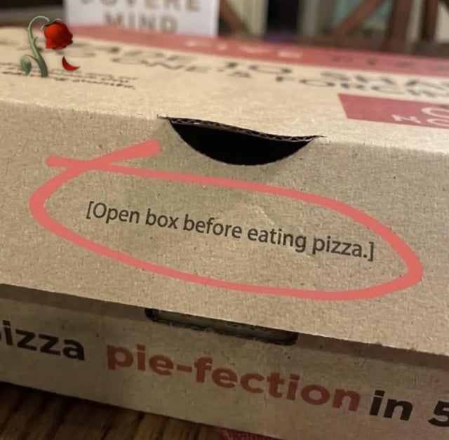The image is a photograph of a standard brown cardboard pizza box, with the clearly printed instruction "[Open box before eating pizza.]" highlighted by a hand-drawn bright pink circle around it. A small digital overlay of a wilted red rose is added to the top left of the box. Part of a second pizza box underneath is visible, showing partial text reading "pizza pie-fection in 5". The meme's humor derives from the absurdly redundant, self-evident nature of the printed instruction, as opening the container to access food is an obvious step no consumer would ever skip, matching the sarcastic tone of the original post title "You dont say… 🤔🥀".