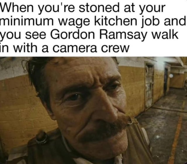 A meme consisting of a top text caption and a photograph. The text reads: 'When you're stoned at your minimum wage kitchen job and you see Gordon Ramsay walk in with a camera crew.' Below the text is a photograph of a man with a mustache, wearing a work uniform, standing in a narrow, dimly lit kitchen hallway with yellow and white tiled walls. The man's expression is tense and wide-eyed, conveying anxiety and surprise, likely reacting to the hypothetical scenario described in the text. The humor stems from the relatable stress of low-wage food service work combined with the added panic of being intoxicated while encountering a famously strict celebrity chef known for criticizing kitchen standards.