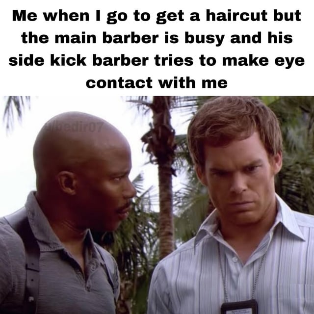 A meme combining a humorous text overlay with a screenshot of two men in a tense stare. The text reads: 'Me when I go to get a haircut but the main barber is busy and his side kick barber tries to make eye contact with me'. The image shows two men in a tropical setting with palm trees, one bald and the other with brown hair, engaged in an intense mutual stare. The meme humorously portrays the awkwardness of unwanted eye contact from a secondary barber when the preferred one is unavailable.