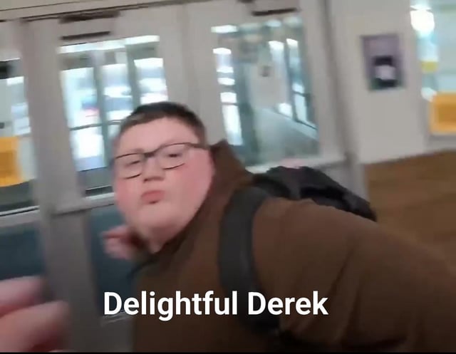 This is a reaction meme featuring a real teen boy captured mid-action with an exaggerated, puckered facial expression, leaning forward playfully toward the camera. The overlaid text "Delightful Derek" at the bottom creates sarcastic humor, contrasting the overly positive name with his goofy, unpolished pose. The background shows a blurred indoor public space, likely a school hallway or transit area with glass doors and wooden flooring. The meme is used to react to silly, ridiculous, or awkward moments, leaning into the irony of the wholesome label paired with the absurd visual.