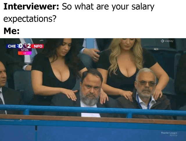 This is a single-panel relatable joke meme themed around job interviews. Text at the top sets up the scenario: first line reads "Interviewer: So what are your salary expectations?", followed by "Me:" to represent the candidate's response. The paired image is a photograph taken in a Premier League stadium VIP box, showing two middle-aged men sitting and staring straight ahead with deliberately stoic, unphased expressions, while two women in low-cut black tops stand directly behind them resting their hands on the men's shoulders as a clear obvious distraction. The joke works as a double entendre: the candidate pretends to be calm and reasonable when asked about salary, while they are secretly focused on wanting an extremely high salary that can afford a luxurious, desirable lifestyle represented by the distracting scene behind the unreacting men.