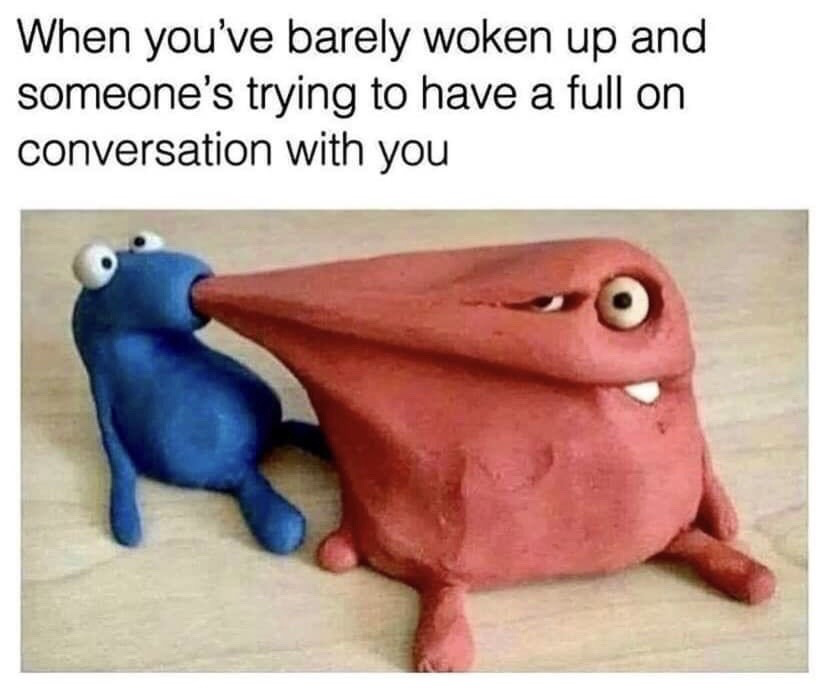 The meme features a text caption at the top that reads 'When you've barely woken up and someone's trying to have a full on conversation with you'. Below the text are two handmade clay figures placed on a light wooden surface: a larger red clay figure with an exhausted, annoyed half-lidded expression, and a smaller, wide-eyed eager blue clay figure holding the red figure's extremely stretched out nose in its mouth. The visual acts as a metaphor for the overbearing, unwanted conversation being forced on the groggy, uninterested person represented by the red figure, creating a humorous, relatable comparison for anyone who has been bothered to talk before they are fully awake.