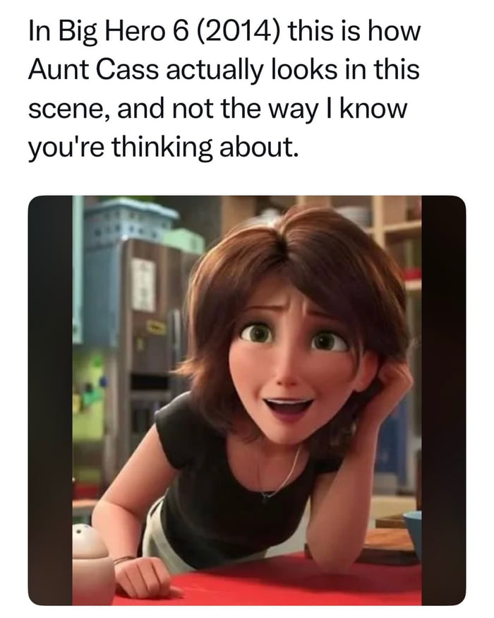 The meme consists of a top text section and an image below. The top text reads: 'In Big Hero 6 (2014) this is how Aunt Cass actually looks in this scene, and not the way I know you're thinking about.' Below the text is a still image of Aunt Cass, a character from the 2014 animated film Big Hero 6. She is leaning forward on a table with her right hand resting on her head, wearing a black shirt, and has a surprised or amused expression with wide eyes and an open mouth. The background shows a kitchen setting with various appliances and items, consistent with her character's role as a café owner in the movie. The text playfully addresses a common perception or meme about Aunt Cass's appearance, clarifying that this is her actual look in the scene, contrasting with how some viewers might imagine or have seen her portrayed in other contexts.