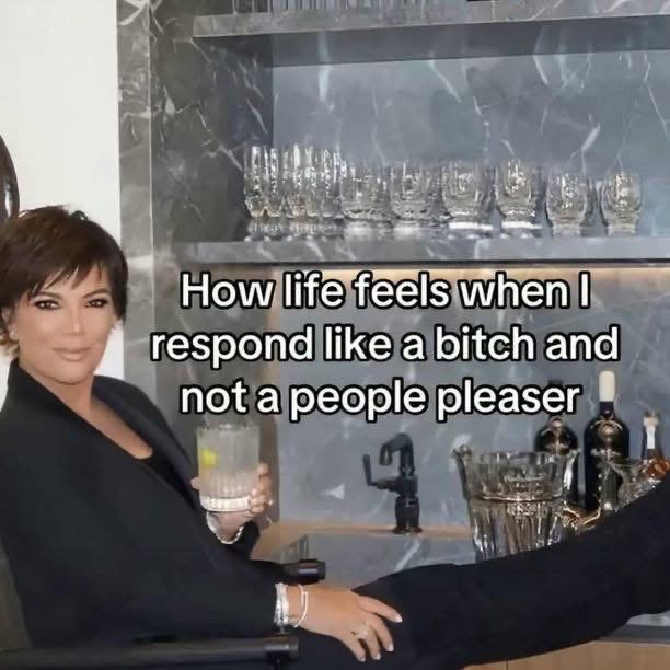 This meme shows Kris Jenner, the well-known matriarch of the Kardashian-Jenner entertainment family, sitting relaxed in a chair in a high-end home bar area. She has her legs propped up on the bar counter, holds a lemon-infused mixed drink in her right hand, and wears a very smug, self-satisfied expression as she looks at the camera. Overlaid large white text with black outline reads 'How life feels when I respond like a bitch and not a people pleaser', humorously conveying the satisfying, carefree feeling of stopping people-pleasing behavior and prioritizing one's own boundaries and comfort over others' expectations.