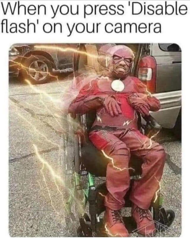 The meme depicts a person dressed in a red The Flash costume—complete with a circular chest emblem and lightning bolt details—sitting in a wheelchair. The individual has a frustrated expression, with eyes closed and mouth downturned. Surrounding the person are bright yellow lightning effects, edited to appear as electrical energy. Above the image, bold text reads: 'When you press 'Disable flash' on your camera'. The humor relies on a pun: 'flash' refers both to the camera's flash function and the DC Comics superhero The Flash, implying that disabling the camera's flash metaphorically 'disables' the speedster, leaving him immobile in a wheelchair.