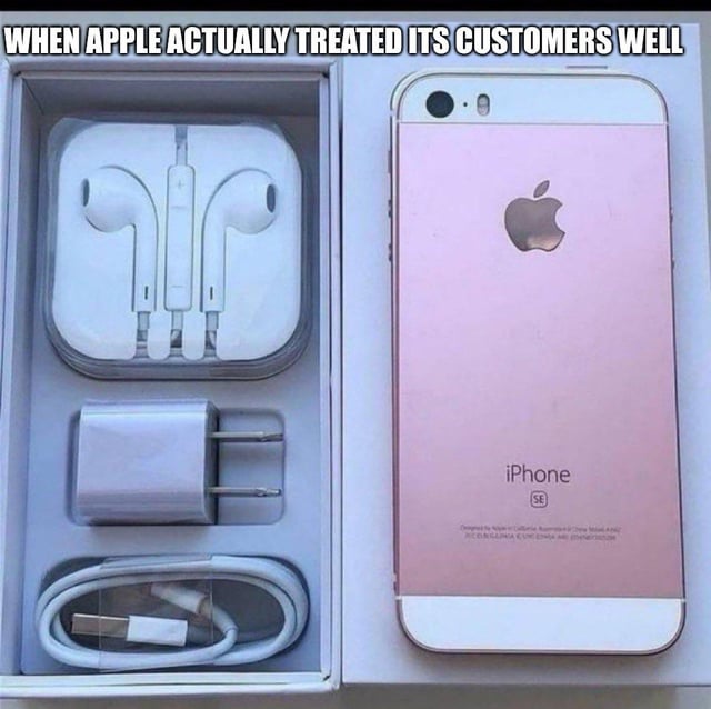 This meme displays a photo of an unboxed pink iPhone SE retail package, showcasing all included accessories: wired earbuds in their protective case, a wall power charger, and a Lightning-to-USB cable. Bold white text at the top of the image reads **WHEN APPLE ACTUALLY TREATED ITS CUSTOMERS WELL**. The content nostalgically contrasts Apple's former practice of shipping iPhones with all necessary complementary accessories against their later policy of selling devices without chargers or earbuds (framed as an environmental measure, but criticized by many as cost-cutting). It taps into consumer nostalgia for more comprehensive product bundles.