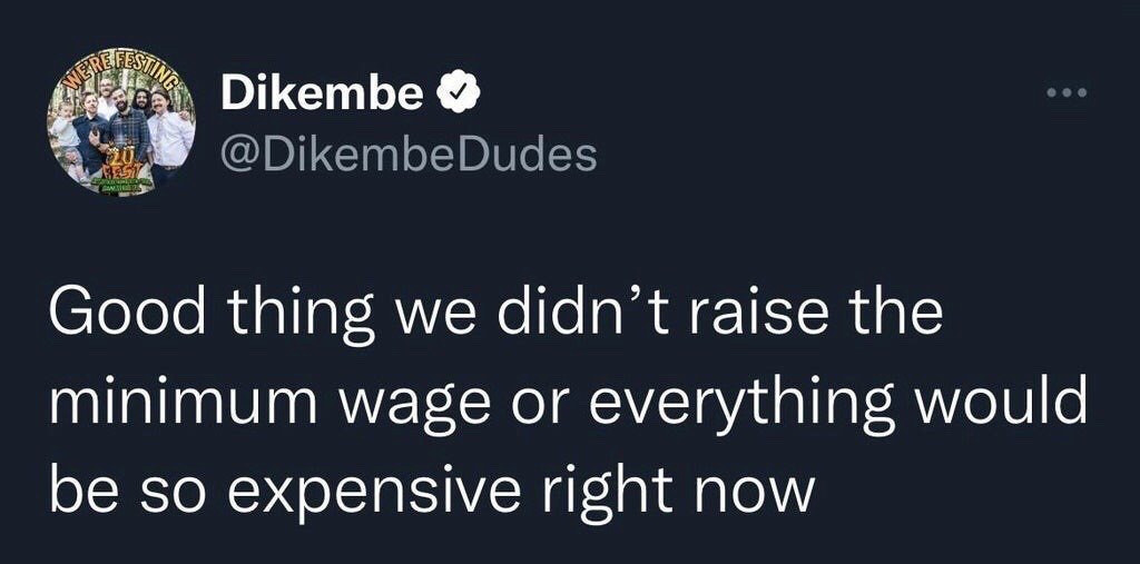 This image is a screenshot of a verified public post from the X (formerly Twitter) account @DikembeDudes. The post features satirical text that reads: 'Good thing we didn't raise the minimum wage or everything would be so expensive right now'. The joke uses sarcasm to mock a common conservative argument against raising minimum wage, which claims that wage increases would cause significant inflation and higher cost of living. The punchline highlights that high cost of living and inflation are already prevalent in the current economic climate, even without minimum wage hikes. The account's profile picture shows a group of smiling men posing together with a 'We're Festing' event graphic overlaid.