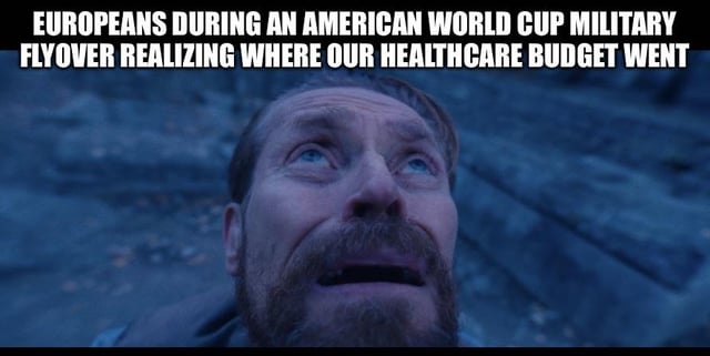 This is a satirical reaction meme using a still shot of the character Magneto (played by Michael Fassbender) from the X-Men film series, who is shown looking upward with a shocked, awe-struck expression and mouth slightly agape. The text overlaid at the top of the image reads 'EUROPEANS DURING AN AMERICAN WORLD CUP MILITARY FLYOVER REALIZING WHERE OUR HEALTHCARE BUDGET WENT'. The joke critiques United States government spending priorities, pointing out that large amounts of public funding are allocated to the military for expensive displays like flyovers at sporting events, while the country lacks robust, affordable public healthcare, leaving European viewers who have access to public healthcare shocked at the misallocation of funds.