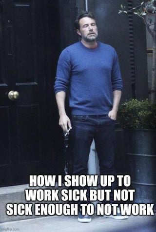 The meme features a well-known paparazzi photograph of actor Ben Affleck standing outside looking visibly exhausted, run-down, and holding a cigarette. Overlaid bold white text at the bottom reads "HOW I SHOW UP TO WORK SICK BUT NOT SICK ENOUGH TO NOT WORK". The meme humorously depicts the relatable, common experience of employees who feel unwell but do not feel ill enough to take a paid sick day, or are pressured to attend work despite being sick, with Affleck's weary demeanor perfectly matching the described mood.