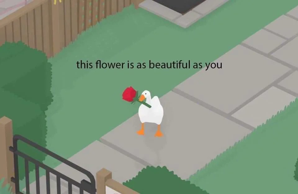 This is a cute wholesome static single-panel meme. It features a cartoon white goose, the protagonist from the video game *Untitled Goose Game*, standing on a residential sidewalk holding a red rose in its beak. The text at the top reads 'this flower is as beautiful as you', delivering a warm, affectionate compliment to the viewer. The background shows a grassy yard, wooden fence, and pathway, creating a gentle, friendly atmosphere.