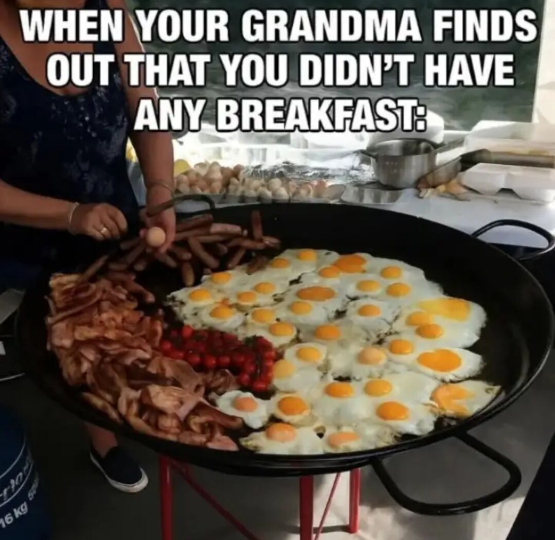 This meme shows an extremely large cooking pan filled with an absurdly massive quantity of fried eggs, cooked bacon, sausages, and cherry tomatoes. A woman, implied to be the grandmother, is standing over the pan and adding another raw egg to the giant breakfast spread. Text overlaid at the top reads "WHEN YOUR GRANDMA FINDS OUT THAT YOU DIDN’T HAVE ANY BREAKFAST:". The joke plays on the common relatable, wholesome stereotype that grandmas always overfeed their grandchildren to ensure they are full and well fed, exaggerating this loving trait for comedic effect.