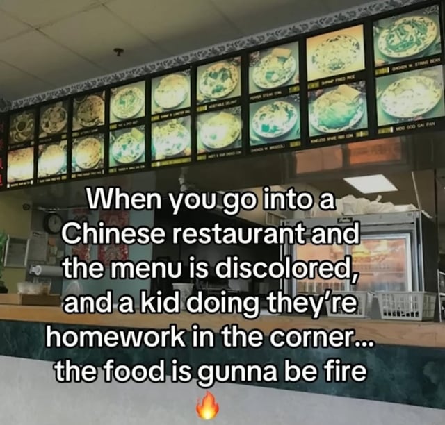 The image depicts the interior of a Chinese restaurant, focusing on a backlit menu board with discolored, possibly aged menu item photos. Overlaid text reads: 'When you go into a Chinese restaurant and the menu is discolored, and a kid doing they’re homework in the corner... the food is gunna be fire' with a small flame emoji at the end. The meme humorously suggests that such 'authentic' signs (discolored menu, family presence) indicate the food will be exceptionally good ('fire' in internet slang).
