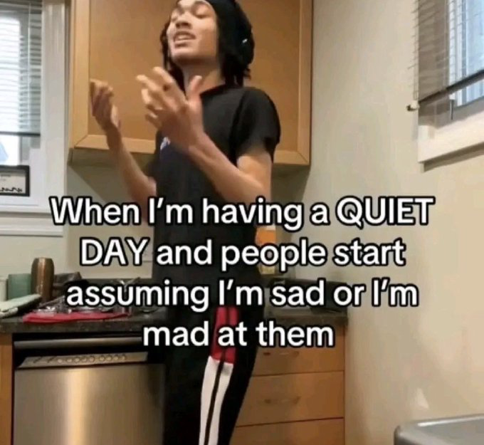 This is a relatable reaction meme featuring a young man standing in a residential kitchen, with his eyes closed, head tilted back, and hands raised near his chest in an exasperated, frustrated gesture. Overlaid bold white text with black outline states 'When I'm having a QUIET DAY and people start assuming I'm sad or I'm mad at them', expressing the common relatable frustration of people who prefer quiet or have calm neutral demeanors having their normal mood incorrectly interpreted as negative emotion directed at others.