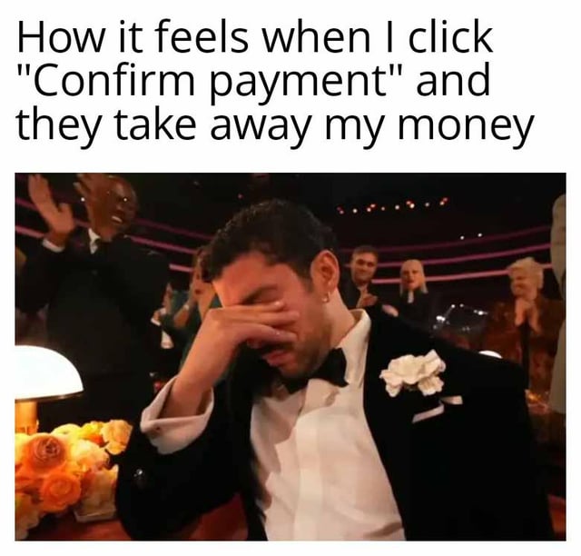 A meme consisting of a screenshot of a man in a black tuxedo with a white boutonniere, seated in an audience (likely at an awards ceremony), covering his face with his hand and appearing visibly distressed/crying. The background features other audience members clapping, creating a contrast between the man's emotional reaction and the celebratory environment. Overlaid text at the top reads: 'How it feels when I click 'Confirm payment' and they take away my money', humorously equating the pain of spending money to an intense emotional moment.