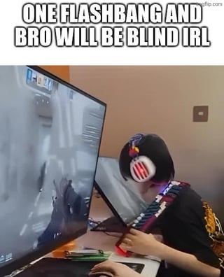 This meme features a young person wearing a gaming headset sitting extremely close, with their face nearly pressed against a computer monitor that displays a first-person shooter game screen washed out by a flashbang effect. The overlaid text jokes that if the in-game flashbang goes off, the person will be blinded in real life because of how close they are to the screen, exaggerating the common FPS game mechanic for comedic effect.
