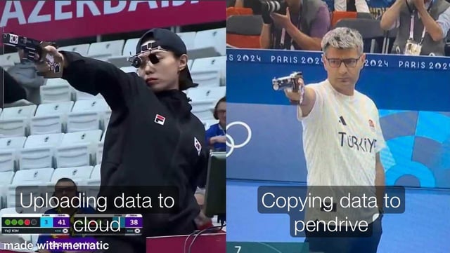 A two-panel meme contrasting cloud storage and pendrive usage. The left panel features an athlete in a shooting stance with the caption 'Uploading data to cloud,' while the right panel shows another athlete (wearing a 'TURKIYE' shirt) in the same stance with 'Copying data to pendrive.' The background includes '2024 PARIS' text, referencing the Olympics. The humor lies in framing traditional (pendrive) vs. modern (cloud) data transfer as competitive 'targeting' actions, playfully questioning continued pendrive use in 2026.
