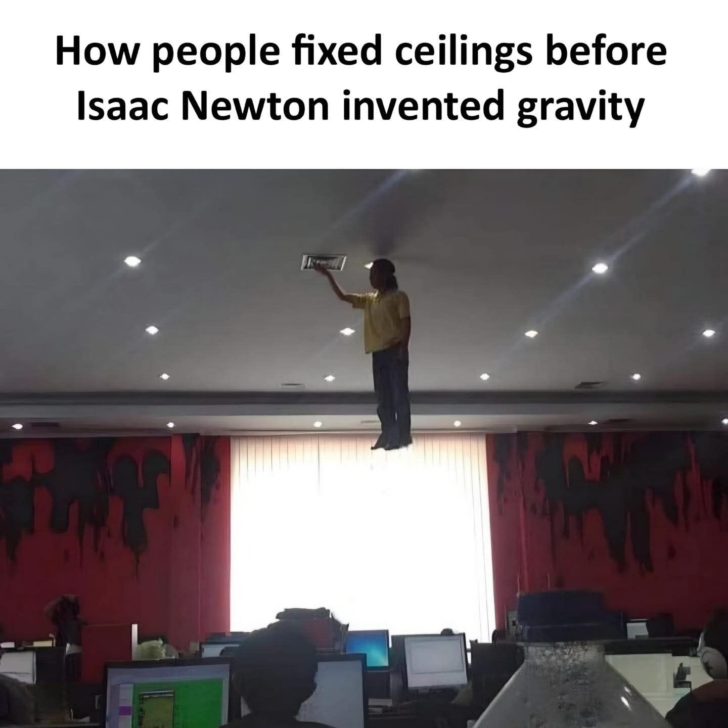 This humorous meme uses a forced perspective optical illusion for comedic effect. The top of the image features text joking that people repaired ceilings by floating up to reach them before Isaac Newton 'invented' gravity. The lower portion is a photo taken from an angle in an office, where a bright backlit window hides the surface a man is standing on, creating the realistic illusion that he is floating unsupported in midair while reaching up to adjust a ceiling vent, with desks, computers, and other office workers visible below him.