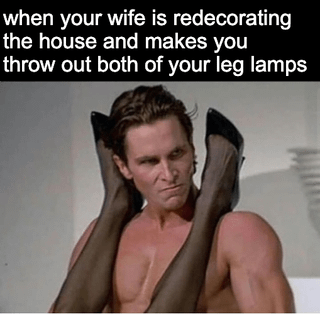 This is a single-panel meme featuring a still of shirtless Christian Bale as Patrick Bateman from *American Psycho*, holding a pair of mannequin legs (wearing stockings and heels) over his shoulders with a stubborn, upset expression. The top text jokes about a husband whose wife is redecorating their home and forcing him to throw out his two novelty 'leg lamps' (unusual kitschy lamps shaped like human legs). The visual gag plays on the legs he's holding looking exactly like the lamps he refuses to get rid of, implying he is hiding or clinging to his beloved weird old possessions he has owned since college.