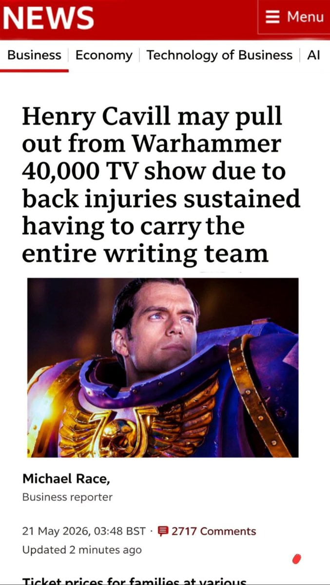 This is a satirical meme formatted to look like a legitimate online news article. Its headline jokes that actor Henry Cavill may pull out of the upcoming Warhammer 40,000 TV series after sustaining back injuries from 'carrying the entire writing team', a literal interpretation of the common idiom meaning to do most of the work for a group to succeed. Below the headline is an edited image of Cavill, a publicly open Warhammer 40k fan attached to star in and produce the Amazon Warhammer 40k series, wearing fictional Space Marine armor from the franchise. The fake article also includes a reporter byline, a false future publication date of 21 May 2026, and a fake comment count to appear more authentic. The joke reflects widespread fan concern that the show's writing team may not properly adapt the dense Warhammer 40k lore, and that Cavill would have to single-handedly uphold the show's quality.