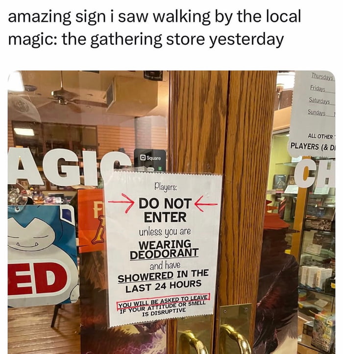 A photograph of the entrance to a local Magic: The Gathering store, featuring a prominent sign taped to the glass door. The sign reads: 'Players: DO NOT ENTER unless you are wearing DEODORANT and have SHOWERED IN THE LAST 24 HOURS. YOU WILL BE ASKED TO LEAVE IF YOUR ATTITUDE OR SMELL IS DISRUPTIVE.' Above the photo, there is text stating: 'amazing sign i saw walking by the local magic: the gathering store yesterday.' The store's interior is visible through the door, showing wooden floors, a ceiling fan, and various merchandise. A Square payment device is mounted near the sign, and partial text 'MAGIC' is visible on the window. Additional signs, including one listing days of the week (likely store hours), are partially visible to the right of the door.