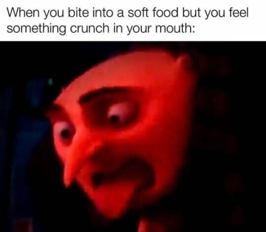 The meme consists of two parts: top text that reads 'When you bite into a soft food but you feel something crunch in your mouth:', followed by a low-resolution, red-tinted close-up of the animated character Count Dracula from the Hotel Transylvania franchise. The character has wide, alarmed eyes and a distressed, horrified grimace, which visually represents the immediate panic, disgust, and alarm people experience when they encounter an unexpected hard, crunchy texture in food they expected to be soft, such as finding a bone fragment, unpopped kernel, seed, or foreign object in their meal.