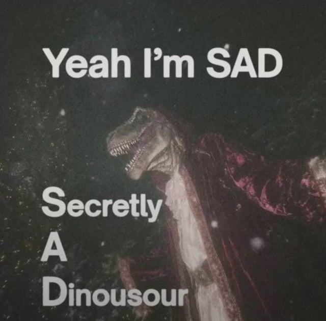 This is a silly pun meme featuring a dark, grainy, lightly snowing background. A person wears a realistic T-Rex dinosaur mask, a dark velvety pink/purple robe over a light-colored nightgown or shirt. Overlaid text forms a humorous acronym pun: the first line reads 'Yeah I'm SAD', with the lines below spelling out SAD as 'Secretly A Dinousour' (with an intentional or unintentional misspelling of 'Dinosaur'). The pun subverts the common meaning of SAD (either the emotion of sadness or Seasonal Affective Disorder) to mean the poster is secretly a dinosaur, for absurd comedic effect.
