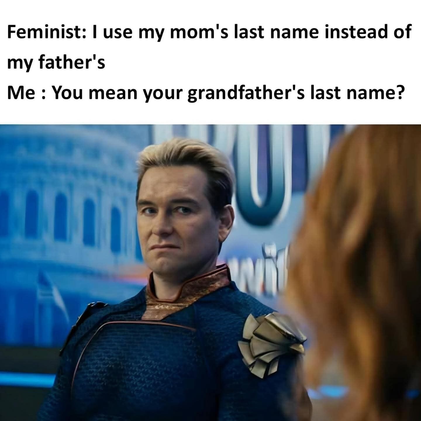 This meme is made up of two lines of text at the top followed by a reaction still of the character Homelander from the TV series *The Boys*. The first line of text states "Feminist: I use my mom's last name instead of my father's", and the second line is a reply reading "Me : You mean your grandfather's last name?". The image of Homelander shows him looking smug, condescending, and satisfied as if he just made a clever gotcha point. The joke highlights the irony that matrilineal last names almost always originate from the maternal grandfather, so the choice to use a mother's last name does not fully escape traditional patriarchal naming conventions.