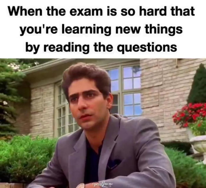 A meme consisting of a top text overlay and a photograph. The text reads: 'When the exam is so hard that you're learning new things by reading the questions'. Below the text is an image of a man with a surprised and confused expression, wearing a gray suit, sitting outdoors in front of a brick house with green bushes and red flowers. The meme humorously depicts the relatable scenario where an exam is so difficult that the test-taker learns new information from the questions themselves, implying a lack of preparation.