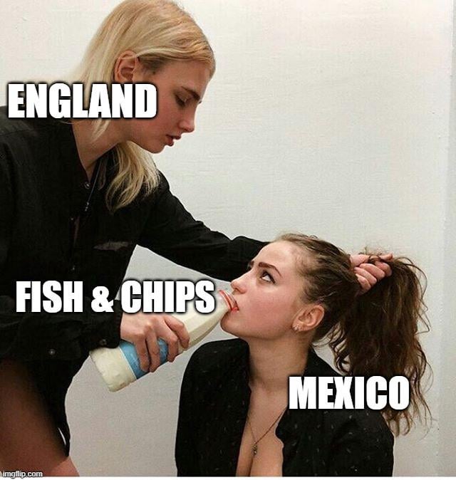 This meme uses a viral candid photograph of a blonde woman holding a second woman by her ponytail and forcing her to drink from a bottle to make a satirical geopolitical joke. The standing blonde woman is labeled 'ENGLAND', the bottle she is holding is labeled 'FISH & CHIPS' (the iconic national dish of England), and the seated woman being forced to drink is labeled 'MEXICO'. The joke parodies the concept of colonial or cultural imposition, framing England as forcing its national cuisine onto Mexico against the latter's will, leaning into the dominant vs. unwilling submissive dynamic of the original photo for humorous effect.