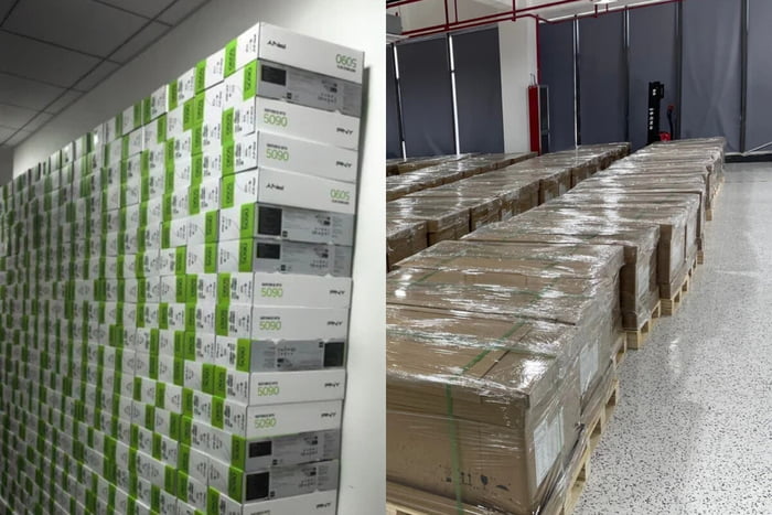 The meme consists of a two-panel collage. The left panel shows a warehouse wall densely packed with white boxes labeled "NVIDIA RTX 5090" (featuring green accents and product branding), creating the appearance of an overwhelming stockpile. The right panel depicts another warehouse area with rows of large, shrink-wrapped pallets, further emphasizing massive inventory. Together, the images humorously contradict the premise of an "RTX 5090 shortage" by visually showcasing an absurdly abundant supply, implying the shortage narrative is exaggerated or false.