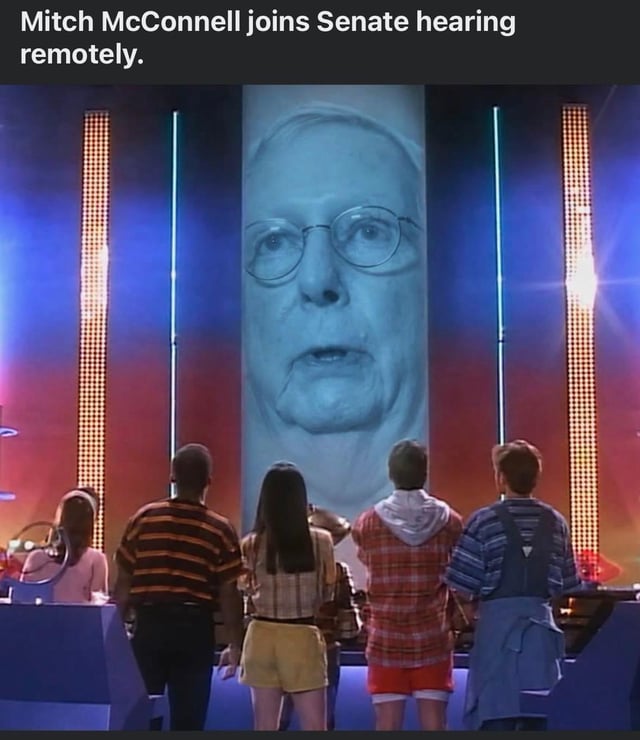 This is a satirical edited meme that repurposes the iconic giant floating disembodied head scene from the 1939 film *The Wizard of Oz*. The head of the Wizard has been replaced with a blue-tinted image of U.S. politician Mitch McConnell. Text at the top of the meme reads 'Mitch McConnell joins Senate hearing remotely.' The main cast of *The Wizard of Oz* (Dorothy, Scarecrow, Tin Man, Cowardly Lion, and others) are shown from the back looking up at the oversized head, parodying the awkwardness and perceived intimidating nature of remote congressional appearances by senior politicians.