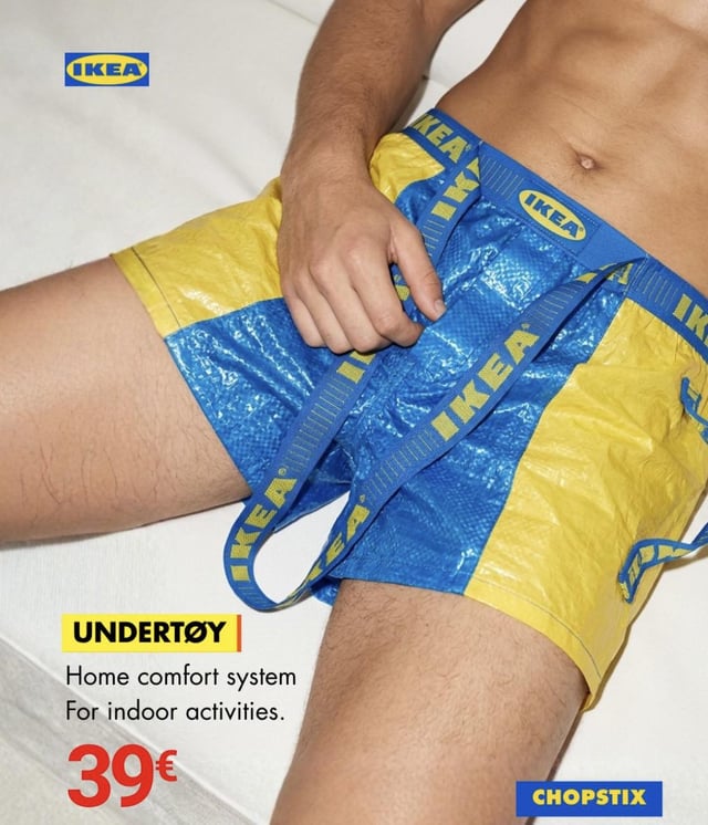 This is a satirical meme formatted as a fake IKEA product advertisement. It shows the lower torso of a shirtless man lying on white bedding, wearing boxer shorts designed to look like they are made from IKEA's iconic blue and yellow woven shopping bag material, with the IKEA logo repeated on the waistband and attached straps. The ad uses IKEA's signature branding style, with the product name "UNDERTØY" using a Scandinavian "ø" character to match IKEA's typical product naming convention, as a pun on the word "underwear". Additional ad text reads "Home comfort system / For indoor activities." with a listed price of 39€. The joke plays on the wide recognition of IKEA's cheap, durable shopping bags and the brand's recognizable product marketing aesthetic.