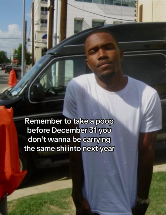 A meme featuring a real man standing outdoors in an urban setting. The background includes a black van, a red traffic cone cover, and buildings. The man, wearing a white t-shirt, stands with his hands in his pockets and has a neutral to slightly serious expression. Overlaid white text on the lower portion of the image reads: 'Remember to take a poop before December 31 you don't wanna be carrying the same shi into next year'. The humor relies on a pun using 'shi' (a slang abbreviation for 'shit') to play on the idea of not carrying over negative things (or literal waste) into the new year.