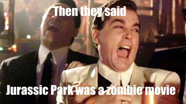 A meme image featuring a screenshot of a man in a white suit with an exaggerated shocked expression, mouth wide open, reacting to an absurd statement. The top text reads 'Then they said' and the bottom text states 'Jurassic Park was a zombie movie,' mocking a dumb or incorrect take about the film Jurassic Park. The background shows other people in a dimly lit setting, possibly a bar or social gathering, enhancing the context of a reaction to a ridiculous claim.