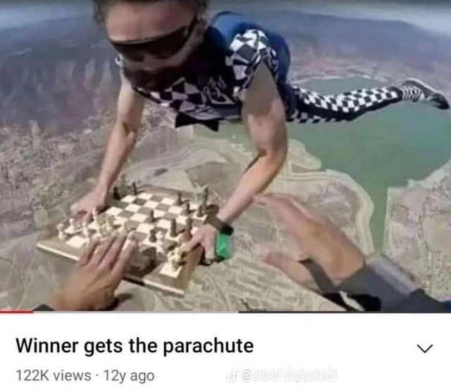 The image depicts two individuals in free fall during a skydiving jump. One person is holding a chessboard with pieces arranged mid-game, while the other appears to be making a move on the board. The background shows a landscape with a body of water and terrain below, emphasizing their high altitude. At the bottom of the image, there is a caption reading 'Winner gets the parachute,' creating a humorous and high-stakes scenario where the outcome of the chess game determines who survives the jump.