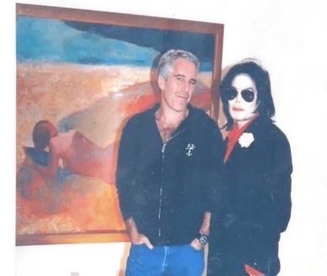 A photograph showing Jeffrey Epstein and Michael Jackson standing side by side in front of a large abstract painting. Epstein is wearing a black zip-up jacket with a small emblem and blue jeans, standing with his hands in his pockets. Michael Jackson is wearing a black outfit with a red scarf and a white flower pinned to his jacket, with sunglasses and his signature hairstyle. The painting behind them features abstract shapes in blue, orange, and red tones with a vague human form.