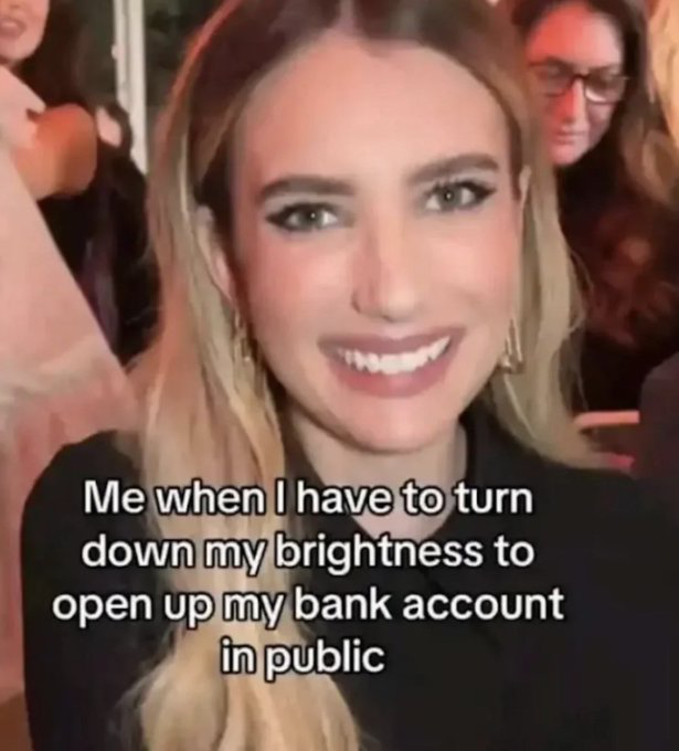 This is a relatable reaction meme featuring a candid shot of actress Emma Roberts giving an exaggerated, forced wide smile, a popular stock reaction image for feigned calm or politeness when internally stressed. White text overlaid on the bottom of the image reads 'Me when I have to turn down my brightness to open up my bank account in public', referencing the common, humorous experience of being embarrassed about low account balances, so users dim their phone screen to prevent strangers in public from seeing their financial status while putting on a fake happy face to hide their dismay at their balance.