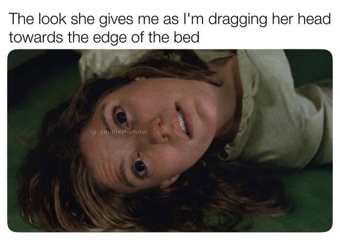 This meme features text at the top that reads 'The look she gives me as I'm dragging her head towards the edge of the bed', paired with a still of the possessed Regan MacNeil character from the 1973 horror film *The Exorcist*. The character is lying upside down on a bed with a wide-eyed, distorted, unsettling grimace, staring directly at the viewer. The humor comes from a suggestive double entendre: the text implies a sexual context of positioning a partner for oral sex, while the horrified, possessed expression of the film character subverts expectations, creating dark, crass humor by implying the partner is disgusted or horrified by the action.