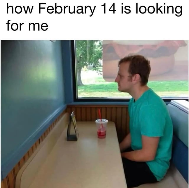 A meme depicting a real man sitting alone in a restaurant booth. He is wearing a teal shirt, with a red drink in a cup with a straw placed on the table in front of him. The man is looking out the window, which shows a grassy area with a tree. Above the image, there is text that reads 'how February 14 is looking for me', referencing Valentine's Day, a holiday associated with romantic relationships. The humor lies in the relatable scenario of being single on Valentine's Day, as the man's solitary setting contrasts with the typical couple-centric celebrations of the holiday.