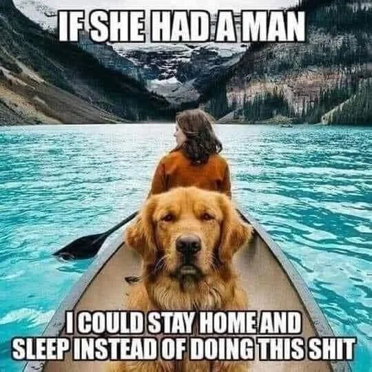 This is a relatable animal meme featuring a woman paddling a canoe on a turquoise alpine lake, with a golden retriever sitting in the front of the canoe staring directly at the camera with a clearly grumpy, unimpressed expression. Large text at the top reads 'IF SHE HAD A MAN', and bold text at the bottom reads 'I COULD STAY HOME AND SLEEP INSTEAD OF DOING THIS SHIT'. The joke frames the dog as annoyed that he has to come along on this outdoor trip because the woman does not have a partner to join her, and he would rather be resting comfortably at home. This captures the relatable mood of people who prefer relaxing over unnecessary outdoor activities.