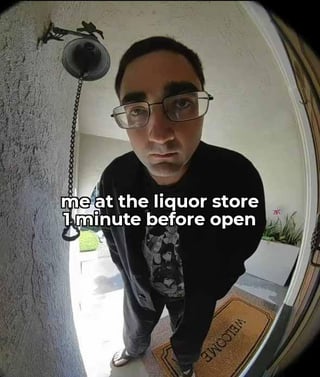 This meme uses a fisheye peephole door camera perspective to show a man with thick black glasses and dark clothing standing on a 'WELCOME' doormat outside a residence, staring intensely directly at the camera with an impatient, deadpan expression. White overlaid text across his chest reads 'me at the liquor store 1 minute before open', creating a humorous comparison between the eagerness and desperation of someone waiting for a liquor store to open and the unsettling, insistent look of a visitor waiting outside a front door for the resident to let them in. The fisheye lens distortion exaggerates the man's facial features, amplifying the comedic intensity of his expression.