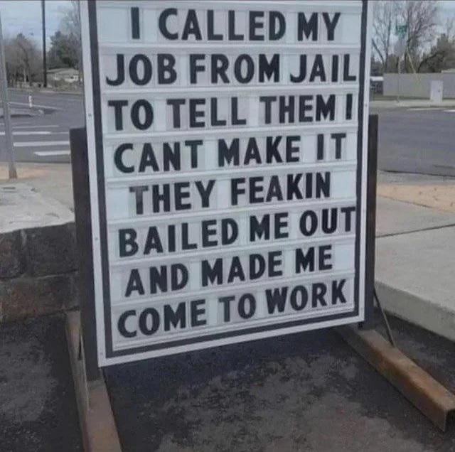 This image shows an outdoor changeable letter sign placed on a sidewalk next to a road, sharing a funny absurd anecdote about extreme job "security". The sign tells the story: the author called their job from jail to say they could not make it to work because of their arrest. In the surprising punchline, the employer bailed the author out of jail just to force them to come into work. The joke flips the concept of job security: it's not that the employee will never lose their job, it's that they literally cannot skip work even when arrested, showing how demanding and inescapable low-wage/regular jobs can be for workers.