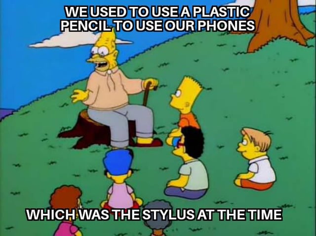 A meme featuring characters from the animated TV show 'The Simpsons.' The scene depicts Abe Simpson (Grampa Simpson) sitting on a tree stump in a grassy outdoor setting, surrounded by children including Bart and Lisa Simpson. Abe is gesturing with one hand while holding a cane, appearing to share a nostalgic story. The image has two text overlays: the top text reads 'WE USED TO USE A PLASTIC PENCIL TO USE OUR PHONES' and the bottom text continues 'WHICH WAS THE STYLUS AT THE TIME.' The humor lies in the playful comparison of using a plastic pencil as a primitive stylus for early touchscreen phones, contrasting with modern stylus technology.